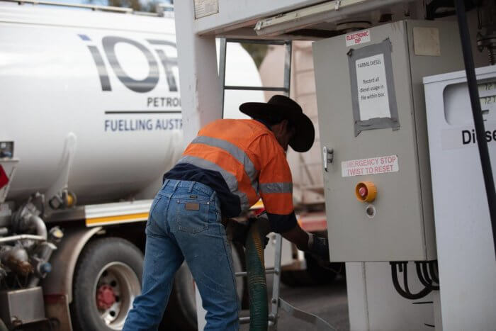 Man wearing high-vis shirt and hat refuelling a bulk fuel storage tank with IOR