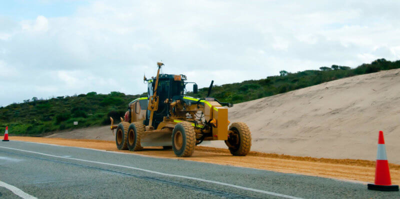 Yellow road grader on the side of a regional Australia road